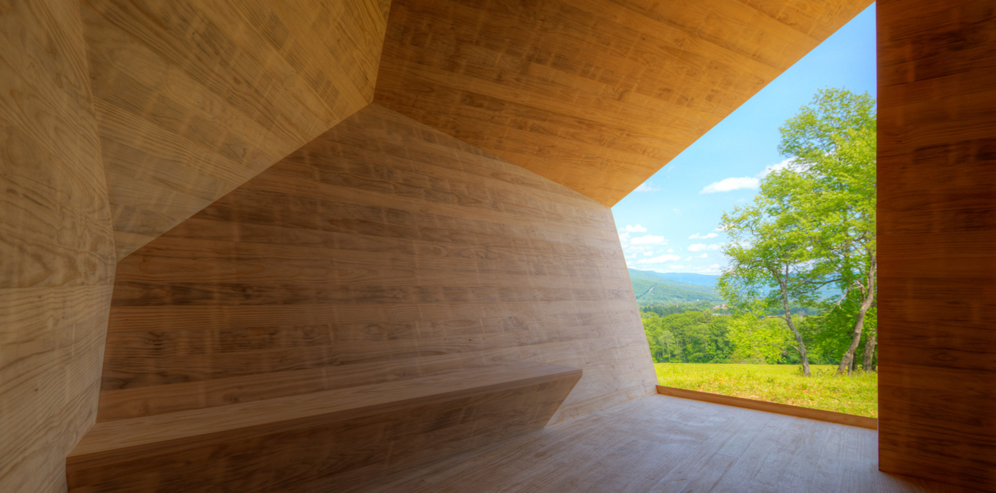 Wooden walls and an opening to the colorful outdoors from the inside of the exhibit 